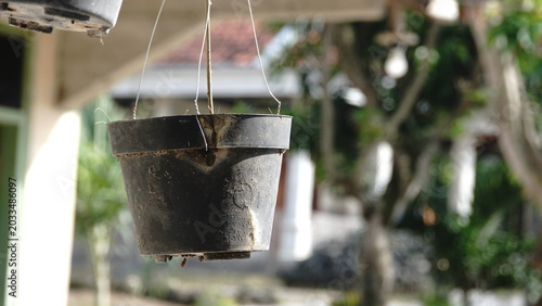 Empty black hanging plant pot in the garden with blurred background