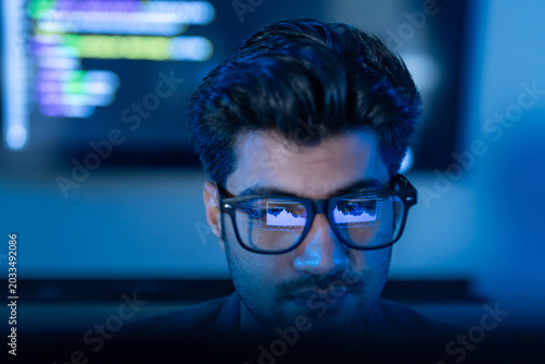 Close-up of male programmer wearing glasses with reflection of financial data chart and coding  Concept of data analysis  software engineering  cybersecurity  stock market trading and business network