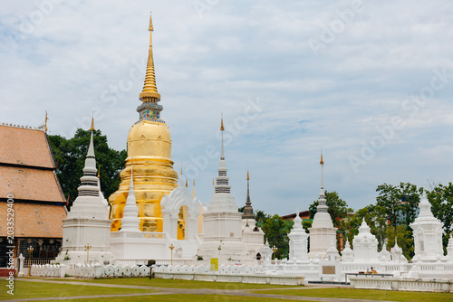 Quadro em tela Golden central stupa with white chedis and temple buildings in grassy courtyard