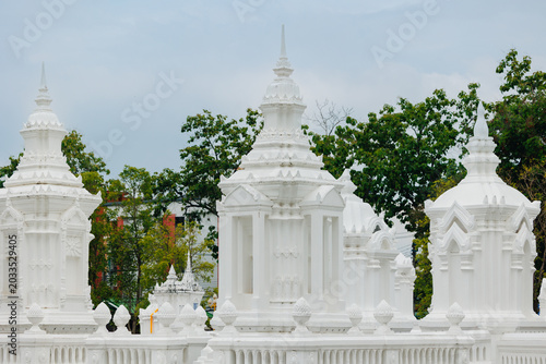 Quadro em tela White thai temple stupas and ornate chedis against trees for cultural architectu