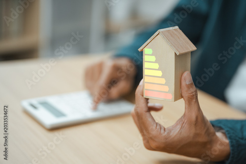 Bilde på lerret Home energy efficiency and renewable sustainability concept with eco house model and energy rating scale for cost savings and green investment planning
