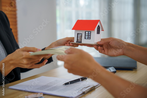 Real estate home purchase mortgage loan property sale contract payment document cash closing captured at office desk hands exchange money beside paperwork professional tone