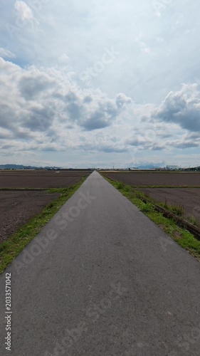 POV shot of moving forward on a single road between empty unplanted rice fields