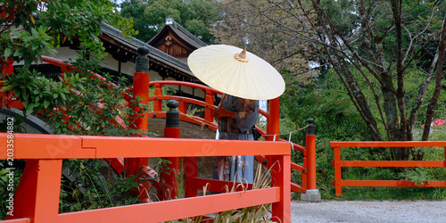 Woman in kimono with wagasa umbrella on red bridge at Kamigamo shrine, Kyoto, Japan