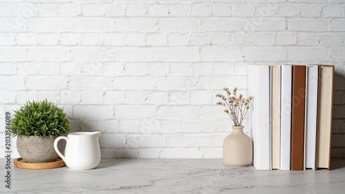  is a minimalist interior photograph featuring a white brick wall as the backdrop. In the foreground, a light gray marble tabletop is visible, adorned with a small arrangement of items. On the left si