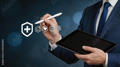 Business professional holding tablet with stylus drawing insurance protection icons including health home heart document settings for financial security risk management coverage