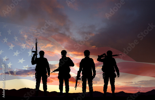 Silhouettes of a soldiers with USA flag against the sunset. Memorial Day, Veterans Day