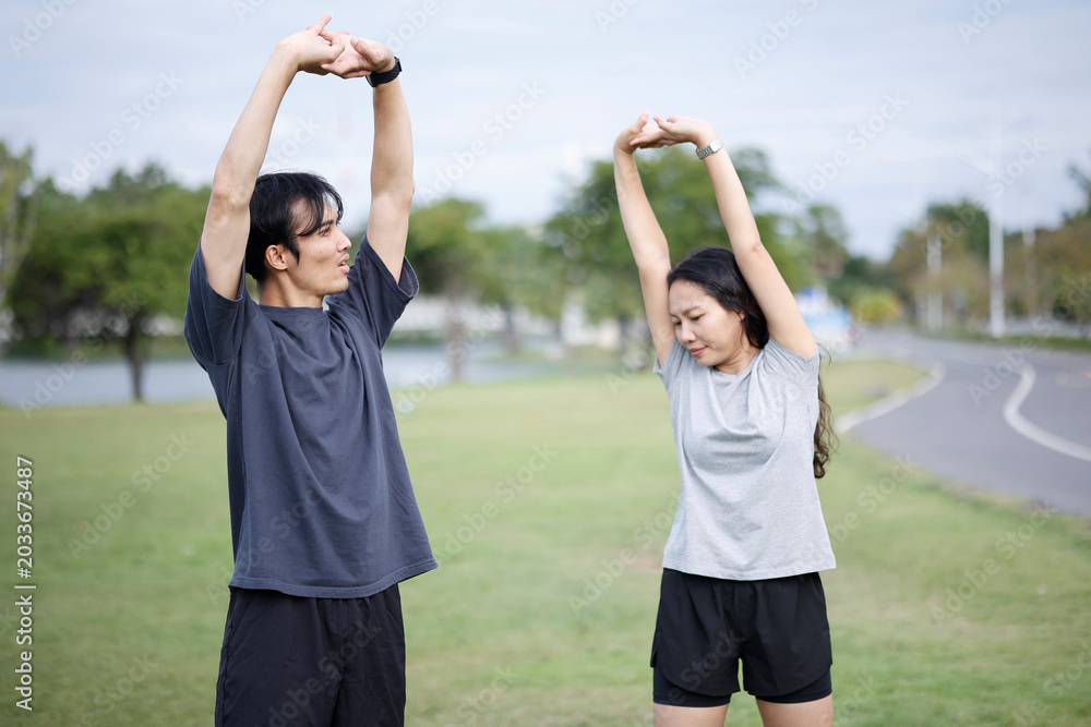 Obraz premium Young Asian Couple Stretching Together Outdoors Before Workout