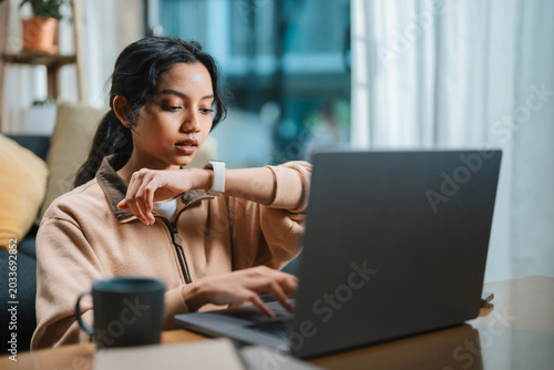 Businesswoman Using Smartwatch While Working From Home