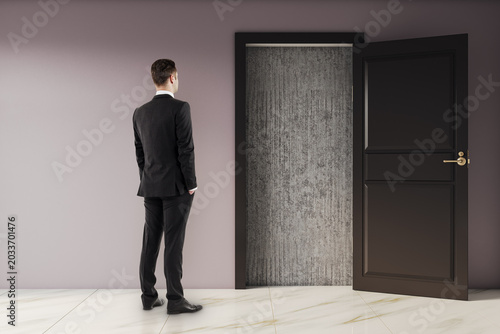 Schilderij op canvas Businessman standing in modern interior looking at open door revealing blocked concrete exit symbolizing deadlock and challenge scenario