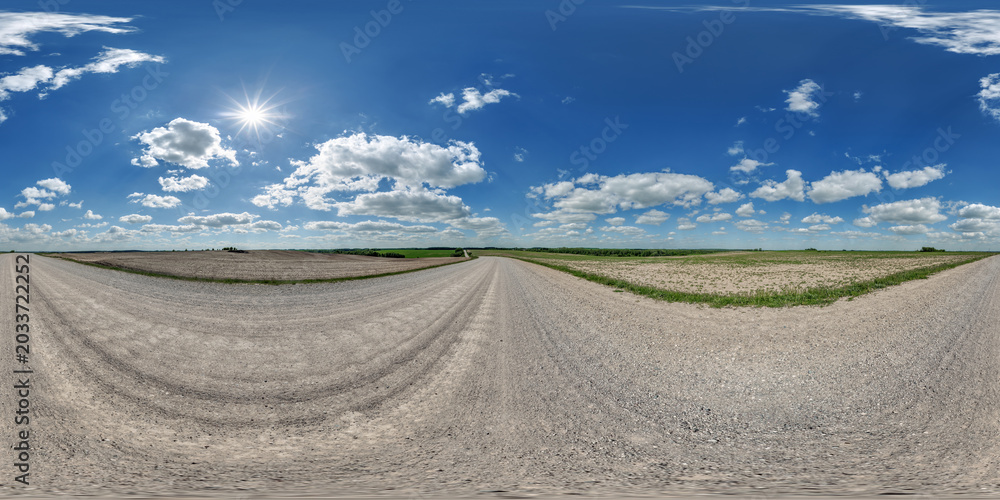 Fototapeta premium hdri 360 panorama view on gravel country roads among fields with beautiful clouds in sky in equirectangular full seamless spherical projection, ready for VR AR or skydome replacement