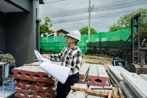 Fotografie House Construction Progress Check
Description: Engineer reviewing blueprints & inspecting detached house construction