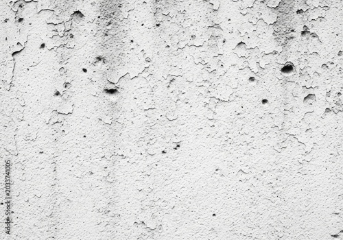 Closeup of a weathered and peeling white wall with black spots and holes
