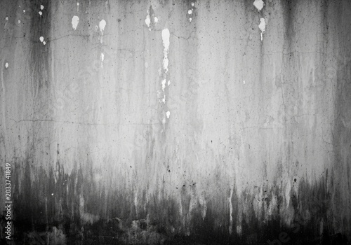 Grunge concrete wall with dark stains and white paint splatters on gray surface