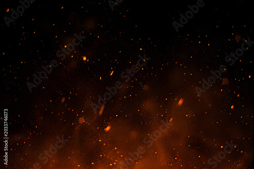 Fiery sparks and embers against a dark black background abstract fire particles