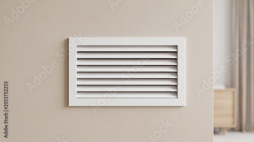 White air vent on a beige wall in a modern room with soft lighting and minimal decoration