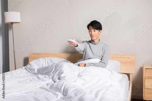 Obraz na płótnie Young man in bed using remote control at home