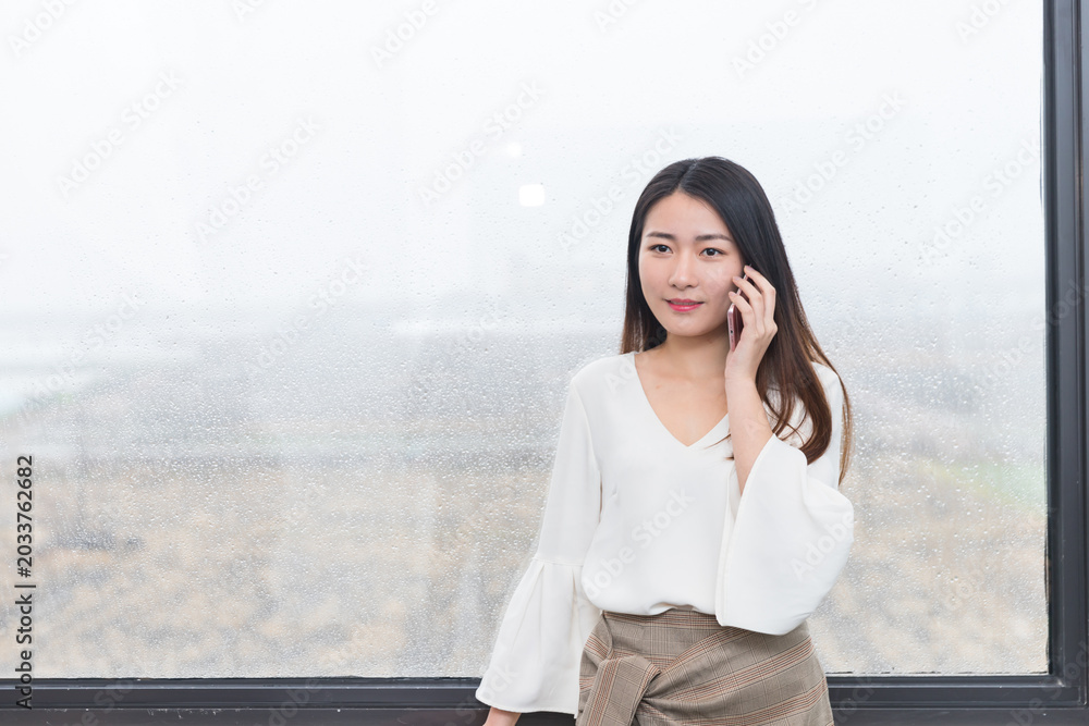 Fototapeta premium Businesswoman talking on phone by rainy office window
