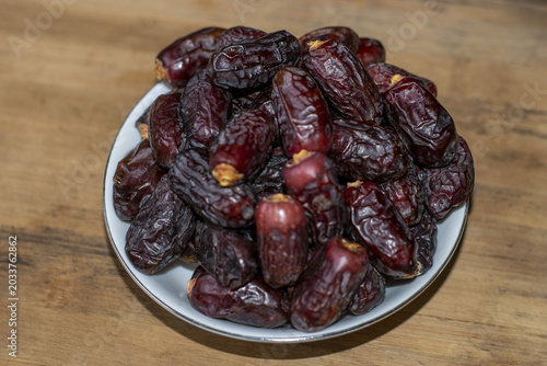 Tablou pe pânză Pile of dried dates in a white bowl on a wooden background