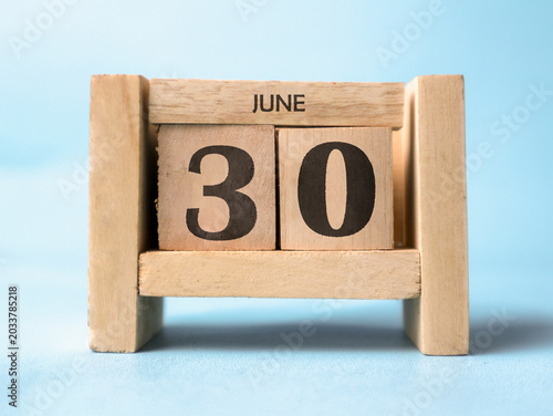 Photos A wooden block calendar for June thirtieth on a light blue background
