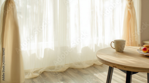 Minimal interior scene with a coffee cup on a wooden table beside soft sunlit curtains. Cozy morning atmosphere with natural light and elegant home decor aesthetic.