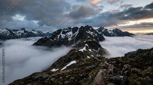 Mountain ridge with melting snow patches emerging through thick morning fog. Dramatic clouds and mist create moody atmospheric highland scenery, scenic landscape with natural textures and destination