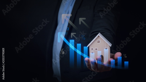 Confident business man holds small wooden house with an upward growth graph showing real estate market recovery after severe recession
