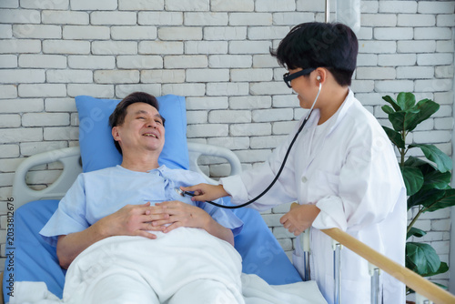 Little in doctor coat playing with stethoscope on Big Smile to asian a man Mid-adult (grandfather) a patient in hospital bed,When I Grow Up A Future Doctor concept