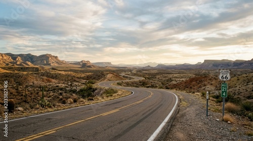 Schilderij op canvas Scenic Route 66 Highway Winding Through Arid Desert Landscape at Sunset
