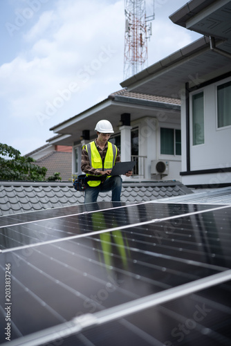 Engineer in safety gear inspecting solar panels with a laptop, monitoring energy production and ensuring optimal performance at a solar panels