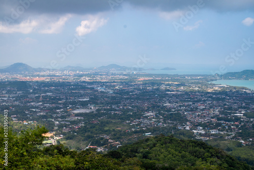 Panoramic aerial view of Phuket city with tropical coastline, ocean bays and dramatic cloudy sky.