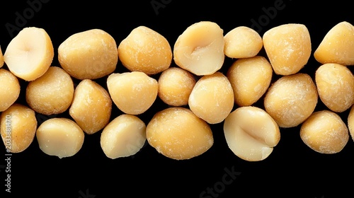 Close-up view of macadamia nuts arranged on a black background.