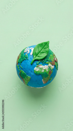 Clay earth globe with green leaf on mint background eco concept
