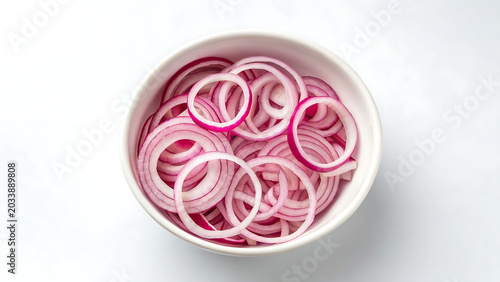 Fresh sliced red onion rings arranged inside a white ceramic bowl on a plain white background, for culinary food, preparation concepts