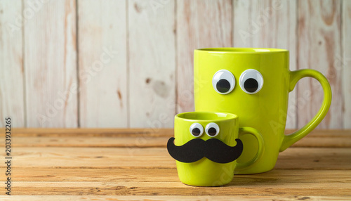 Father and Son Mugs: Two lime green mugs, one larger than the other, decorated with googly eyes and a mustache on the smaller one, resembling a father and son duo.