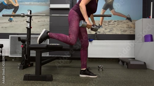 Elderly woman exercising with dumbbell in gym environment 