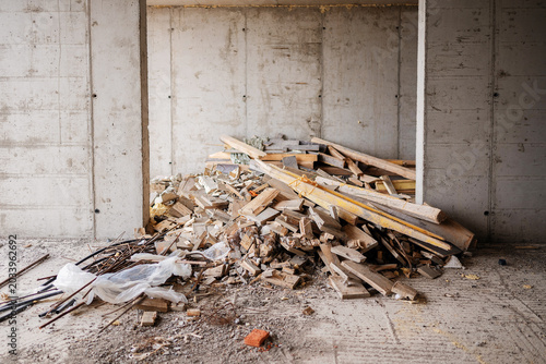 Konstfotografi A large pile of construction waste, wood lumber scraps, and debris inside an unfinished concrete building room during a cleanup or renovation phase