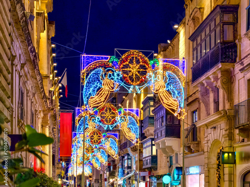 Valletta, Malta, festively illuminated old town alley with christmas decoration and historic balconies