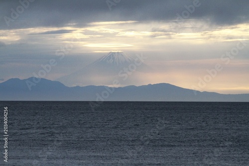 Ethereal view of Mount Fuji emerging through twilight clouds over Tateyama bay.