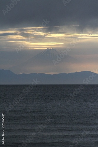 Mystical Mount Fuji emerging through twilight clouds over Tateyama bay in spring.