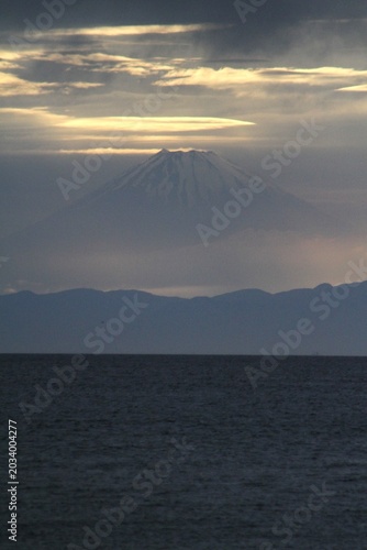 春の霞の中にそびえ立つ夕暮れの富士山の雄大なシルエット（縦位置）