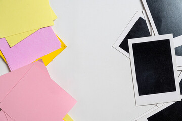 Creative top-down view of blank instant film frames and colorful pink and yellow sticky notes on a white glittery background, perfect for design mockups and memory concepts