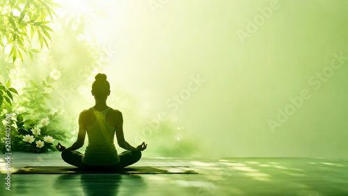 Peaceful human silhouette in lotus pose meditating at the center of soft pastel green background banner for International Yoga Day