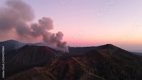 Dramatic aerial view of volcanic eruption with smoke and sunset sky.
