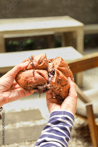 Hands hold split, golden-brown bread with moist interior