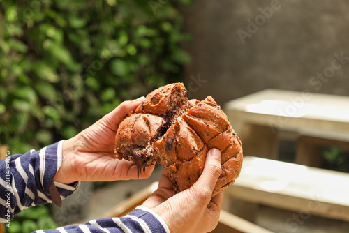 Hands hold split, golden-brown bread with moist interior