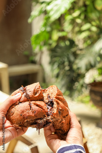 Hands hold split, golden-brown bread with moist interior