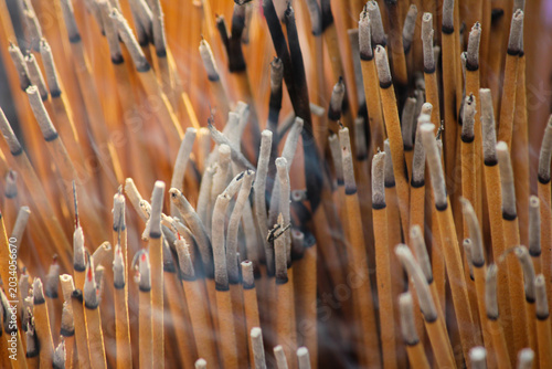 Close-Up Of Burned Incense Sticks With Smoke Rising In A Temple Ritual Offering