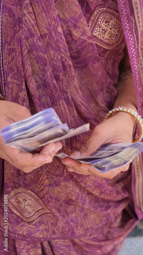 Indian woman's hands counting a stack of Indian Rupee banknotes