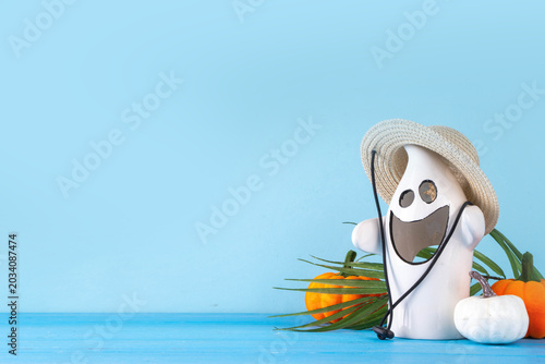 Summerween holiday background. Bright festive background for summer Halloween holiday in style of Halloween with summer decorations, pumpkins, ghost, bat, summer vacation accessories, tropical leaves